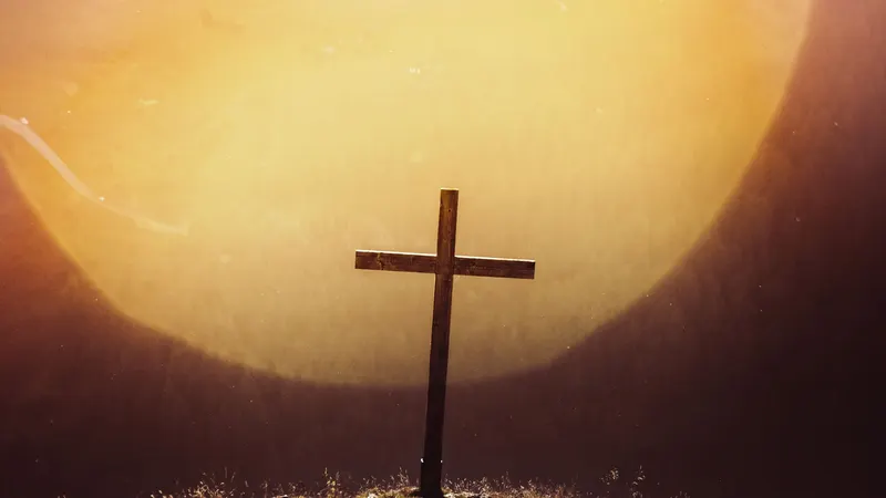 Una cruz de madera recortada contra el sol